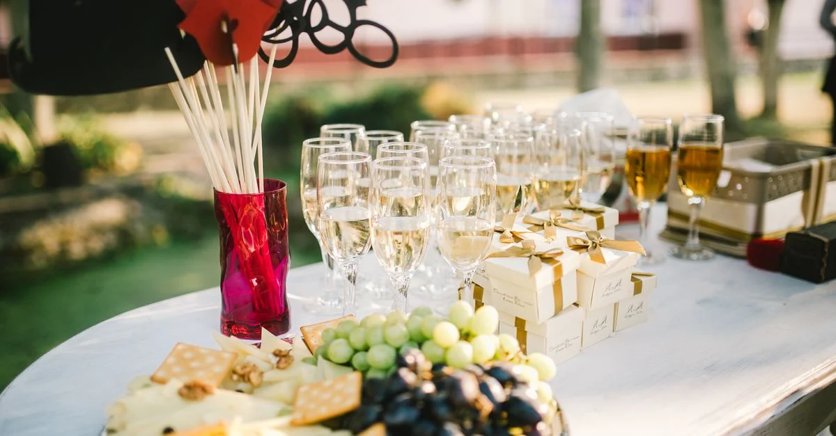 Una elegante disposición al aire libre con queso, uvas y copas de champán para un evento de celebración.