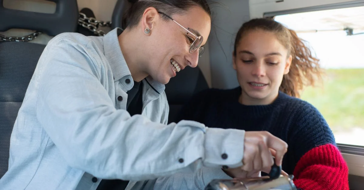 Una pareja alegre sirve café en una autocaravana, capturando un momento de viaje acogedor.