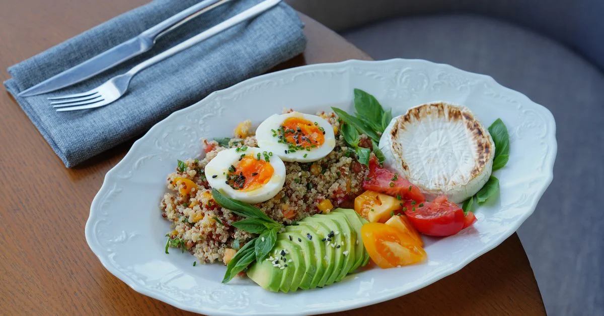 Deliciosa ensalada de quinoa con aguacate en rodajas, huevos pasados por agua y hierbas frescas.