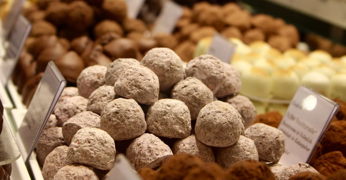 Una variedad de deliciosas trufas de chocolate en exhibición en una tienda de confitería con etiquetas.