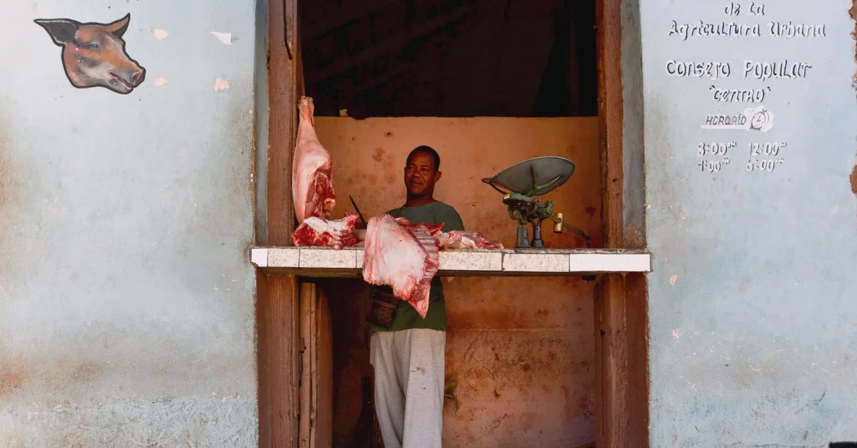 Une boucherie traditionnelle affichant des morceaux de viande frais avec un homme au comptoir.