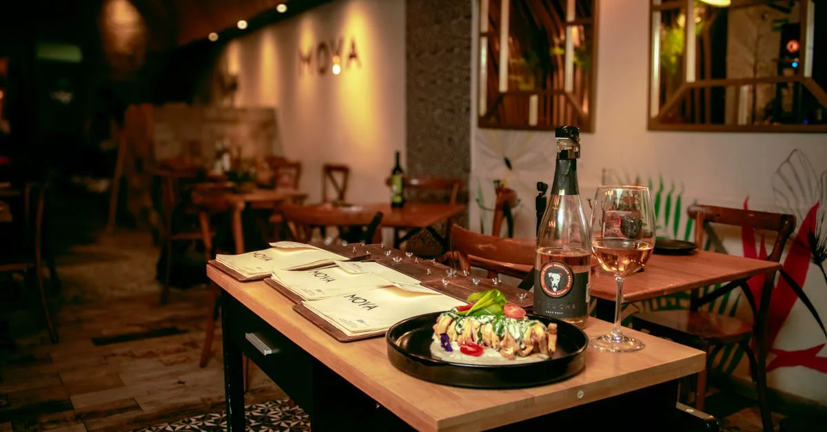 Acogedora mesa de restaurante con plato gourmet y vino, creando un ambiente cálido para cenar.