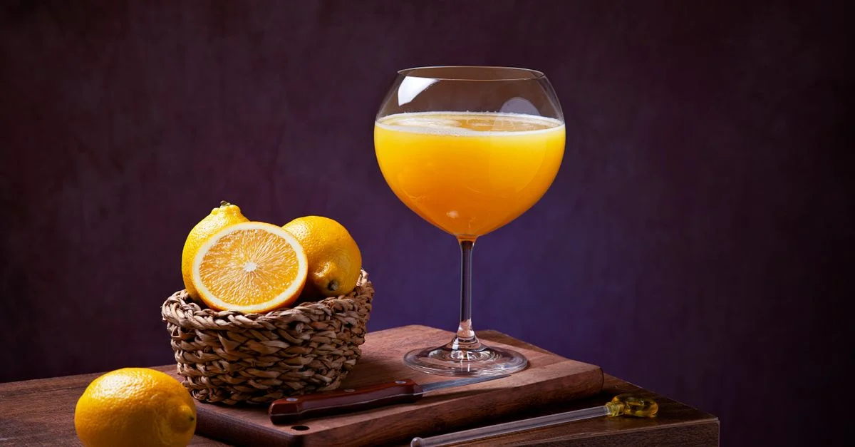 Jugo de naranja y limones sobre una tabla de madera, perfecto para temas de bebidas refrescantes.
