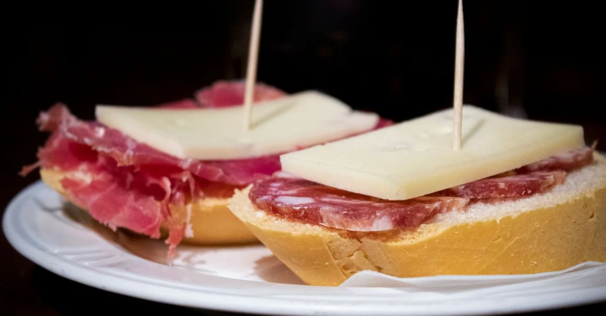 Vista cercana de tapas tradicionales españolas con salami y queso en un plato.