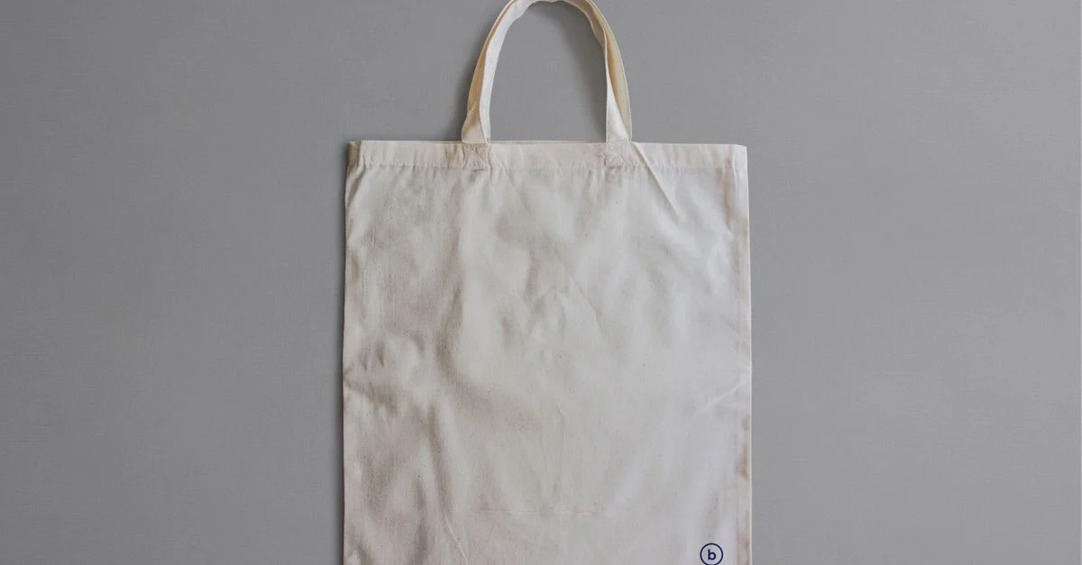 Bolsa tote de lona blanca simple para exhibición de productos o branding.