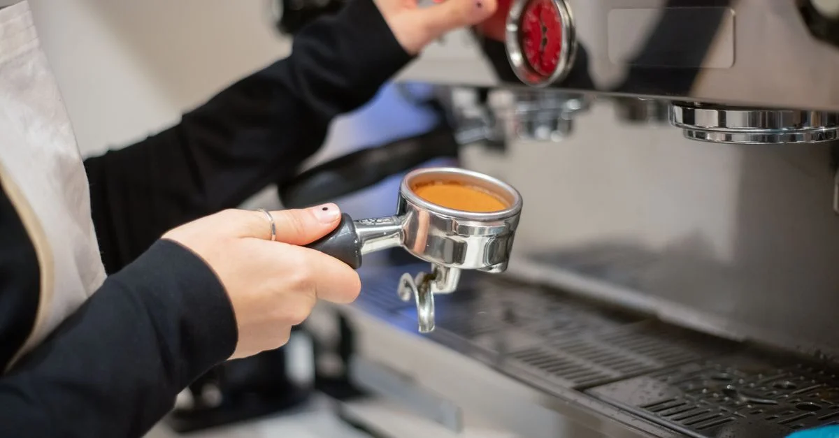 Un barista prepara café utilizando una máquina de espresso en un ambiente acogedor de café.