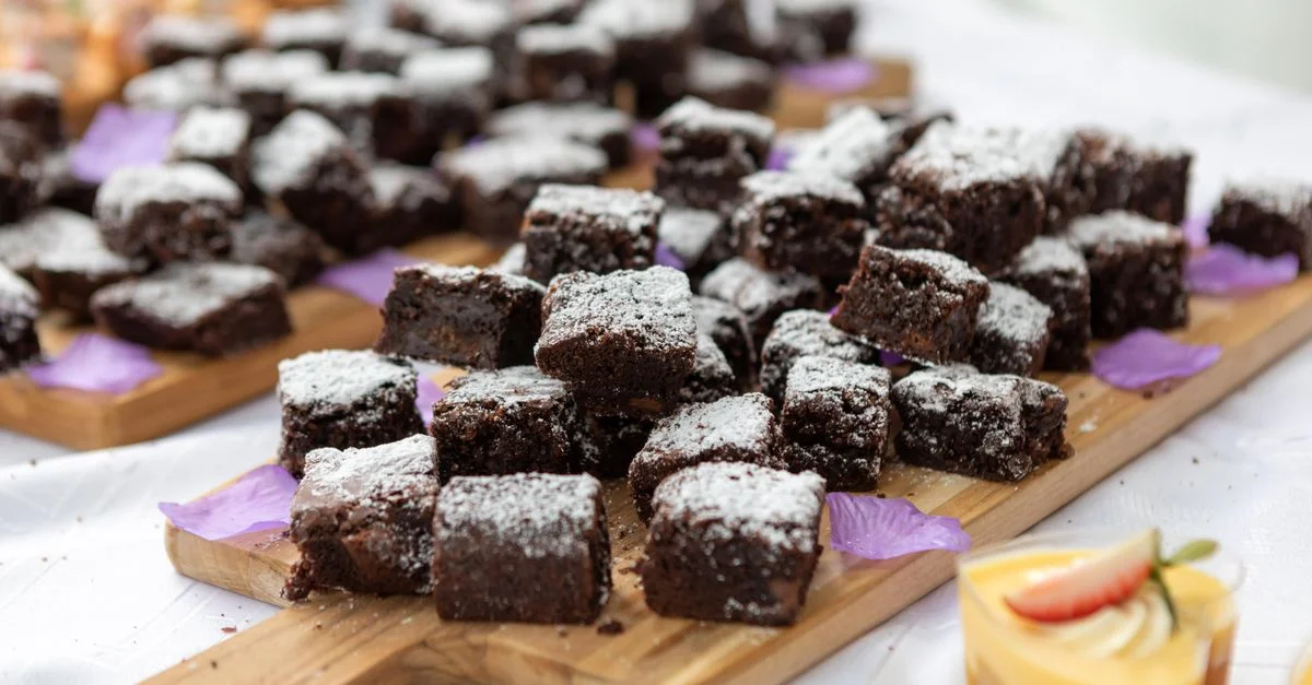 Primer plano de brownies de chocolate espolvoreados con azúcar glas en una tabla de madera. Configuración perfecta para un postre.