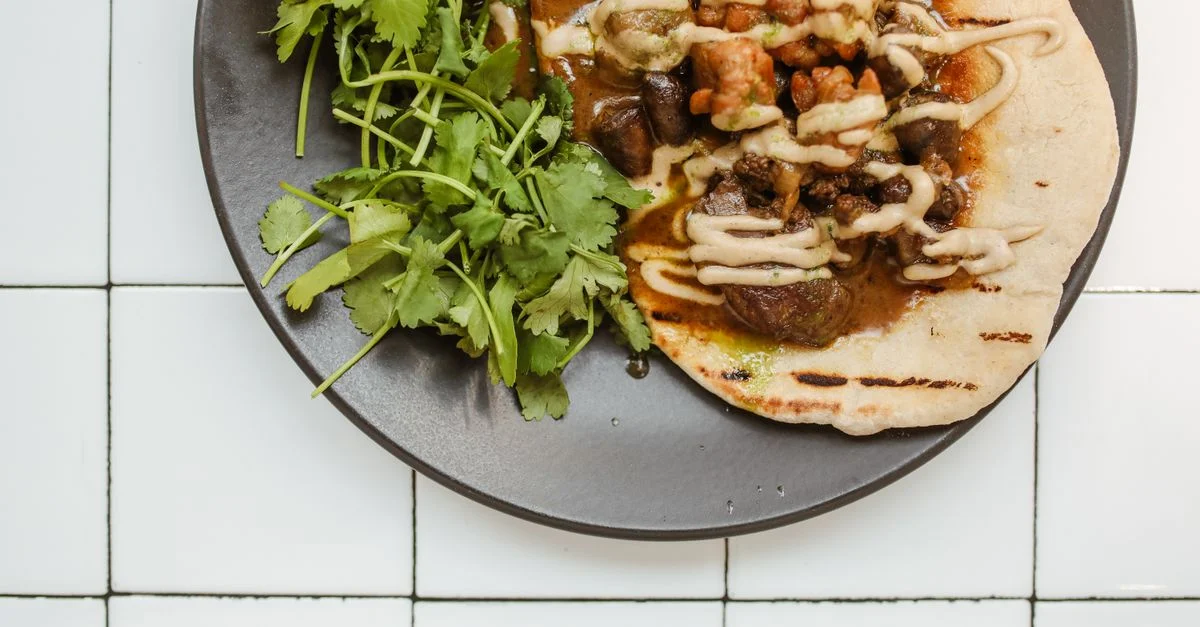 Primer plano de un sabroso curry de carne sobre roti con hierbas frescas, perfecto para una comida gourmet.