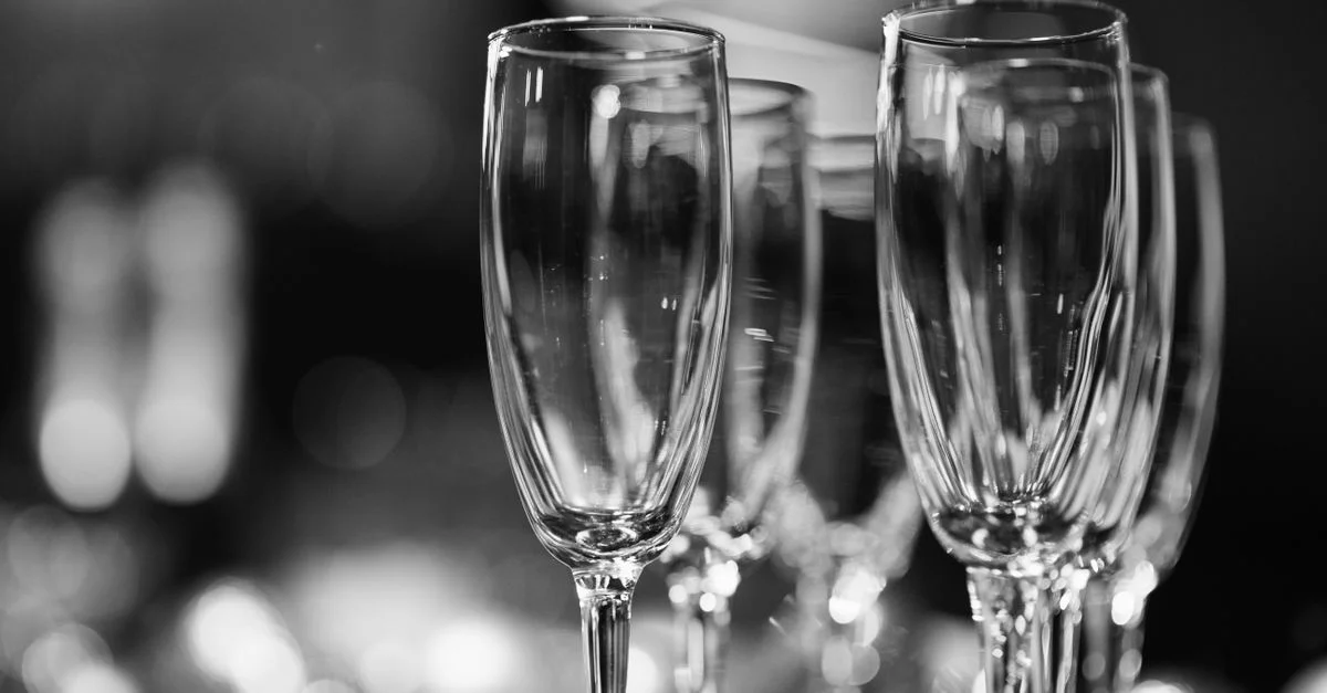Imagen en blanco y negro de copas de champán con un fondo bokeh difuminado, perfecta para ocasiones elegantes.