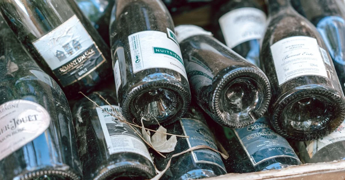 Una colección de botellas de vino y champán vacías en una caja, listas para reciclar.