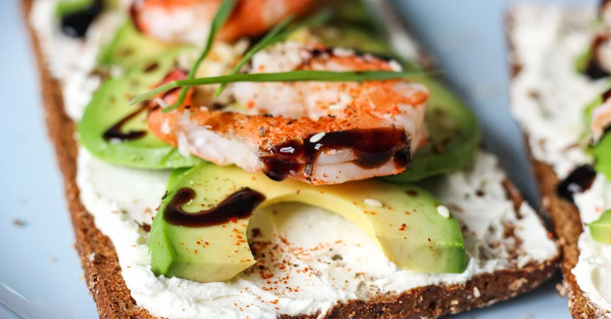 Deliciosa tostada de camarones y aguacate con queso crema, perfecta para una comida ligera.