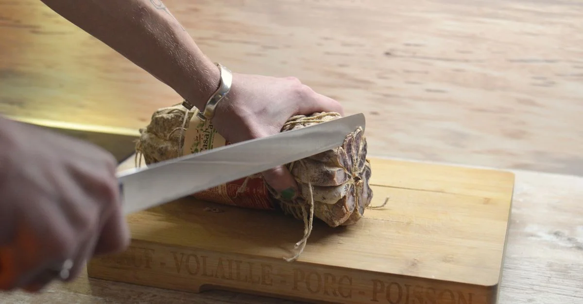 Primer plano de cortar jamón francés en una tabla de madera en la cocina de Provenza, Francia.