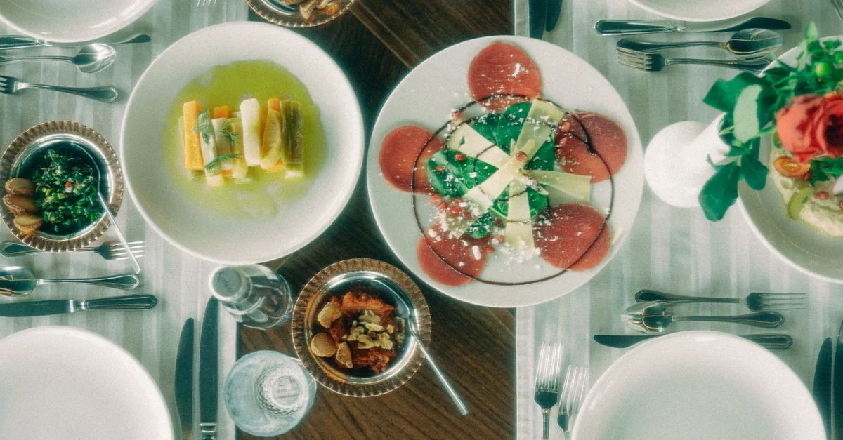 Vista aérea de una mesa de comedor finamente dispuesta con una variedad de platos gourmet y vajilla elegante.