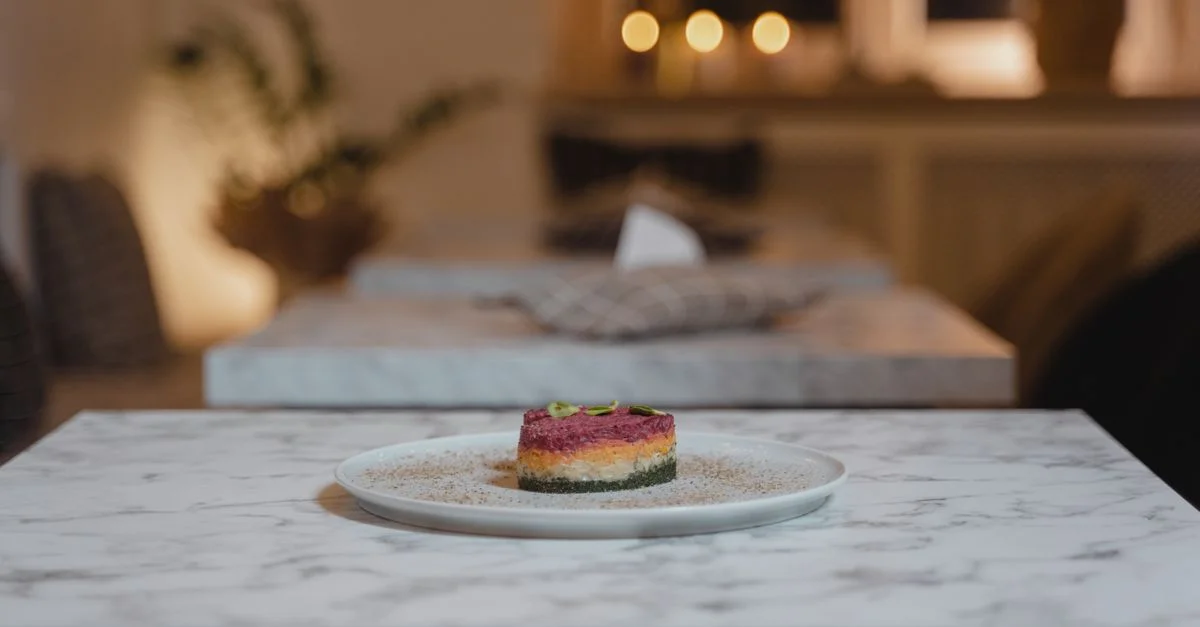 Un plato gourmet bellamente presentado en una mesa de mármol en un acogedor ambiente de restaurante con iluminación cálida.