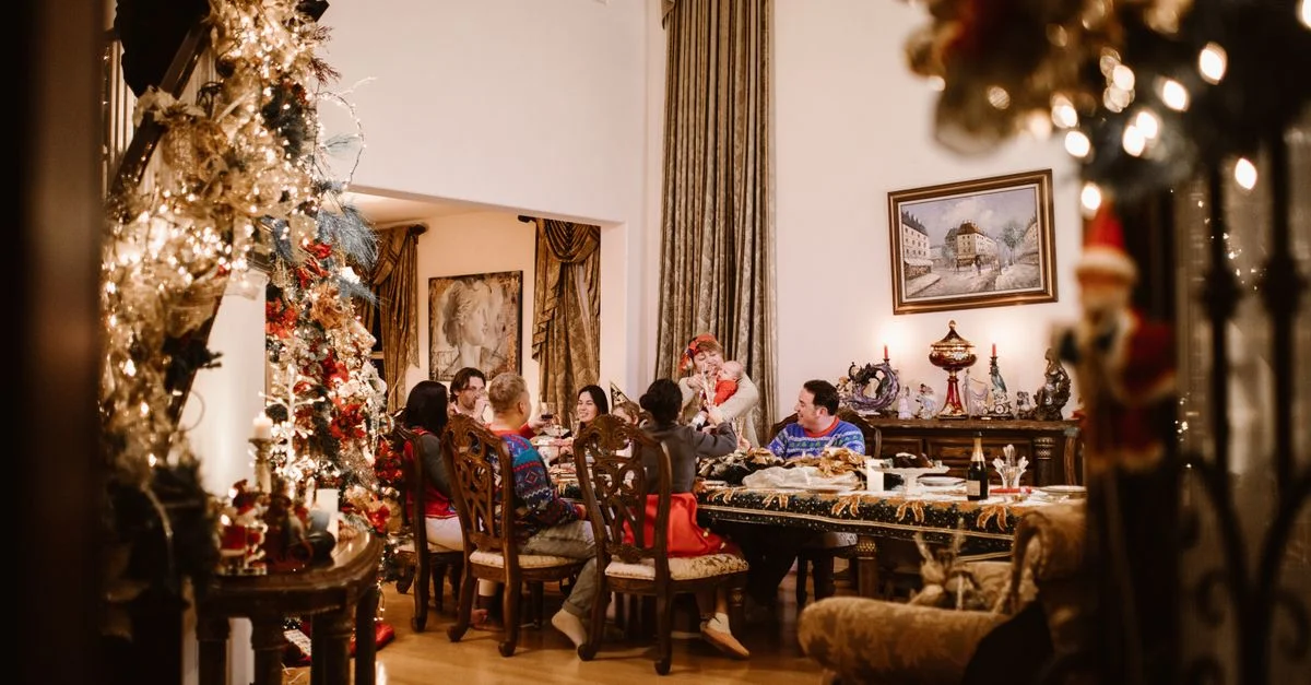 Una familia alegre disfrutando de la cena de Navidad en un hogar cálidamente decorado con un árbol bellamente iluminado.