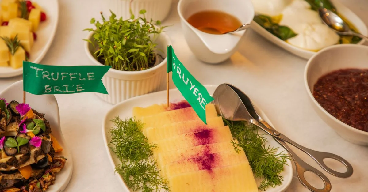 Una presentación estilizada con brie de trufa y queso gruyere en un plato gourmet con hierbas frescas.