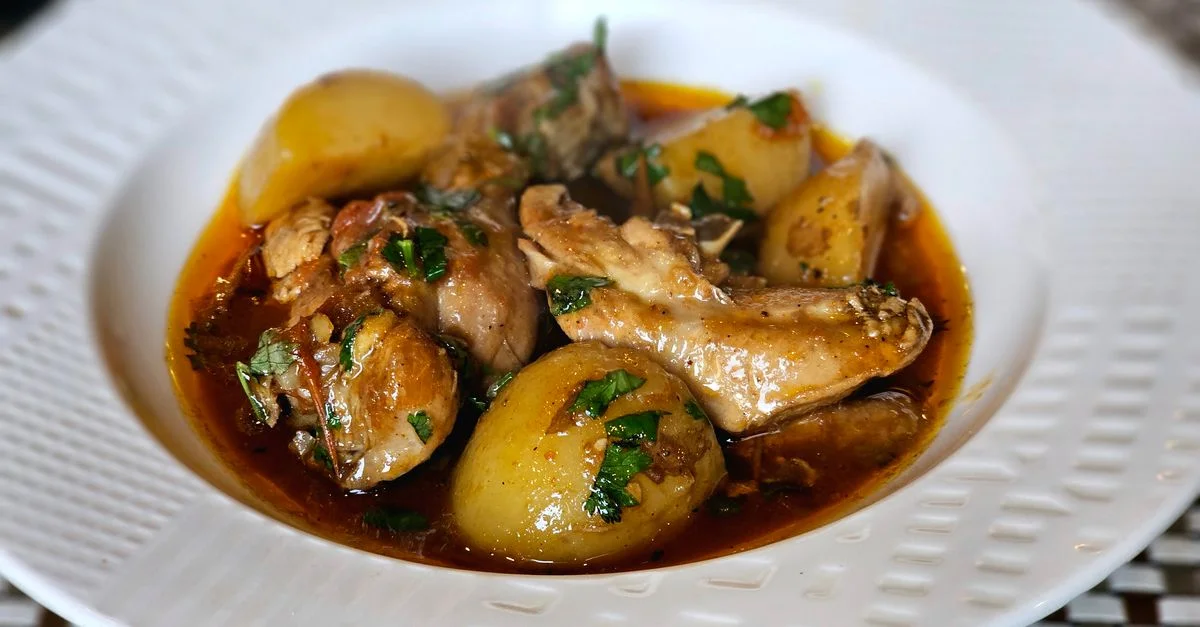 Un delicioso plato de estofado de pollo con patatas y hierbas, perfecto para una comida acogedora.
