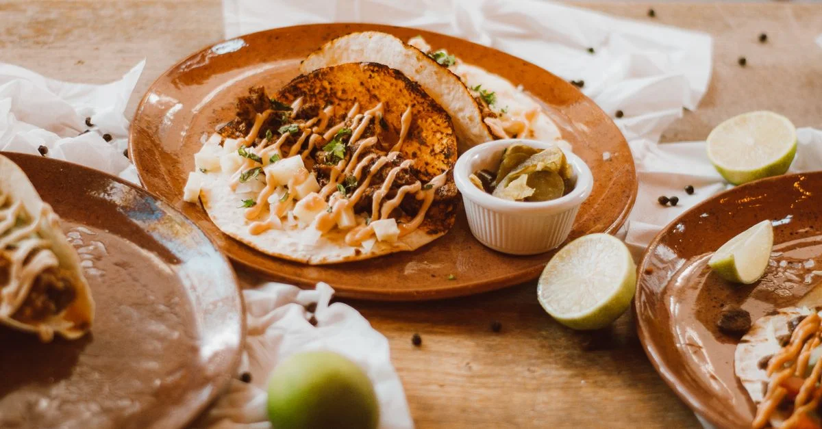 Deliciosos tacos mexicanos servidos con lima y salsa en platos rústicos. Perfecto para entusiastas de la fotografía de alimentos.