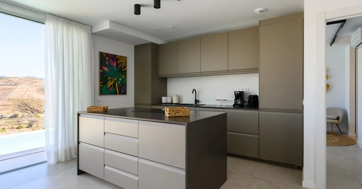 Un interior de cocina elegante y minimalista con gabinetes modernos y una impresionante vista exterior.