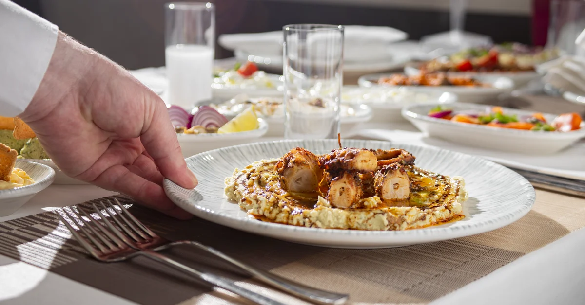 Primer plano de un plato gourmet de pulpo servido en una elegante mesa de comedor.