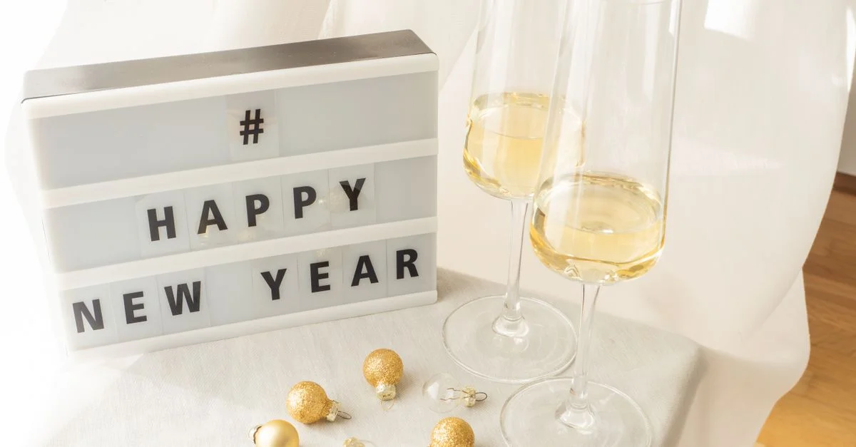 Configuración alegre de Año Nuevo con copas de champán y decoración festiva en una mesa brillante.