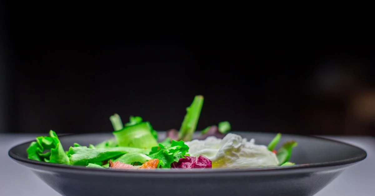 Primer plano de una colorida ensalada de jardín fresca en un elegante cuenco negro.