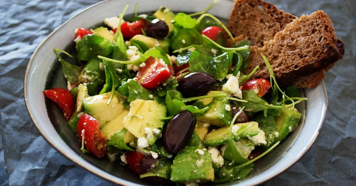 Deliciosa ensalada griega con aguacate, feta y aceitunas, ideal para una comida saludable.
