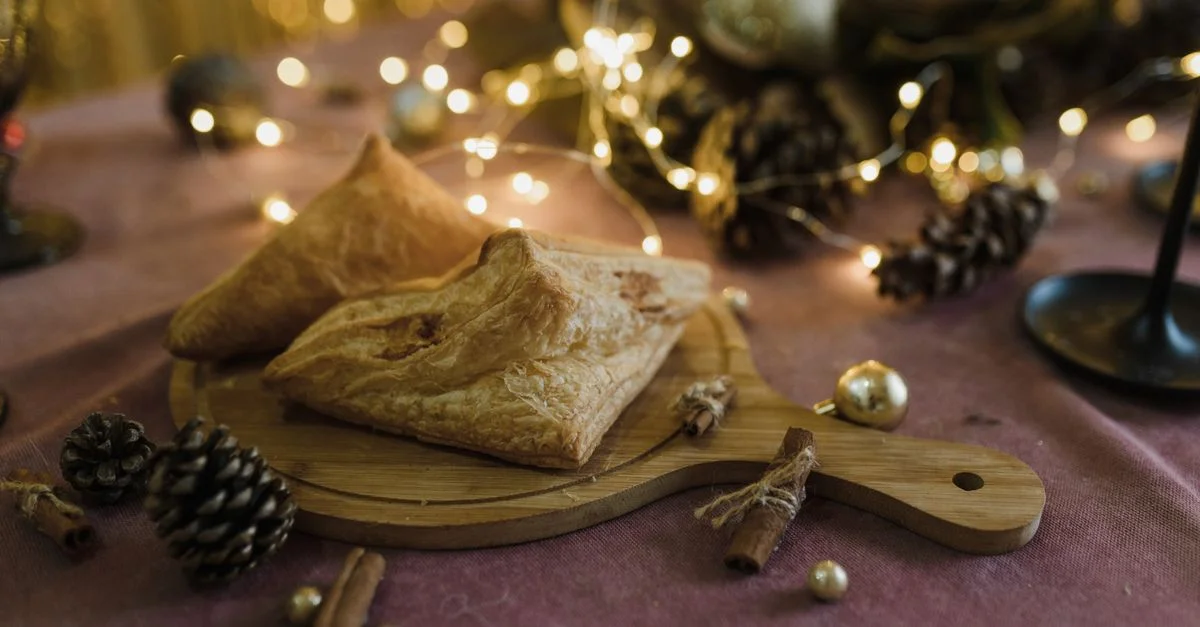 Deliciosos pasteles en una tabla de madera rodeados de decoración navideña y luces bokeh.