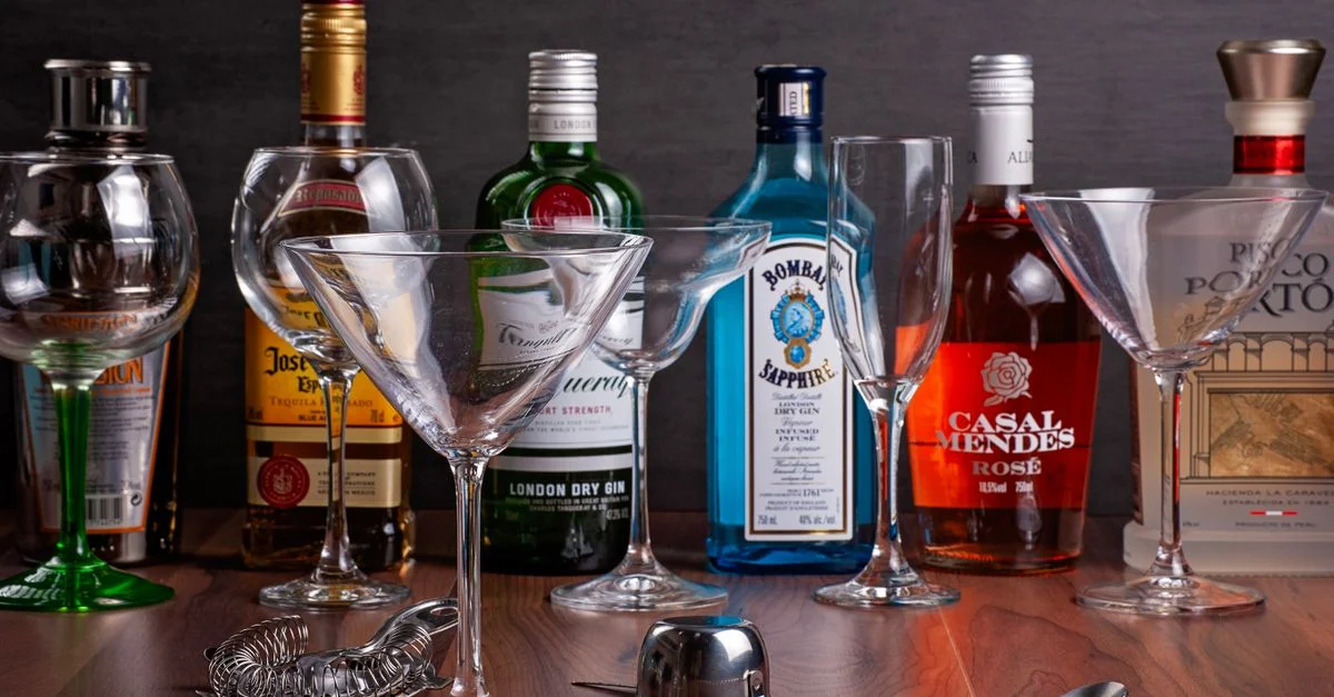 Botellas de licor assortidas con copas de cóctel sobre una superficie de madera - perfecto para temas de bar.