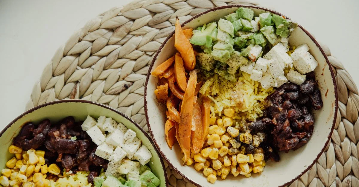 Vista desde arriba de tazones vegetarianos con aguacate, maíz, frijoles y queso para una comida deliciosa.