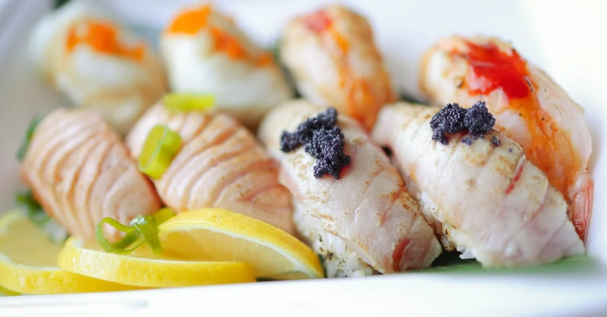 Gros plan d'une assiette de sushis joliment disposée avec diverses garnitures et des tranches de citron.